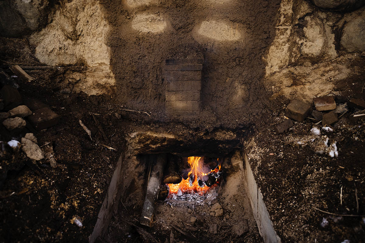 炭焼き窯の入り口で薪を燃やしている様子