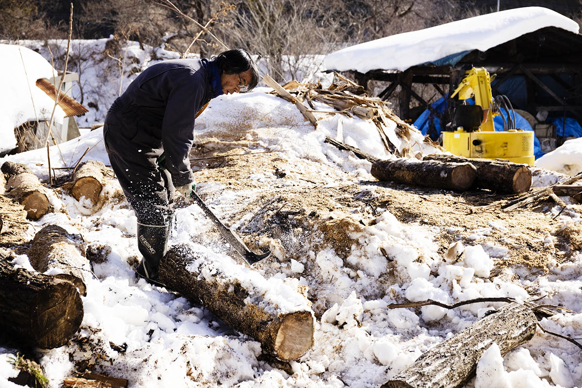 材木に付いた雪を払う炭焼き職人